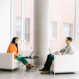 Two students meet in a brightly lit space